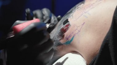 Dövmeci adamın omzuna dövme yaptırıyor.