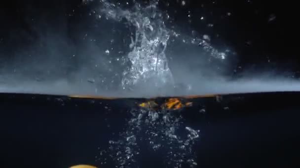 Съемка падающей гранадильи в воде с дымом — стоковое видео