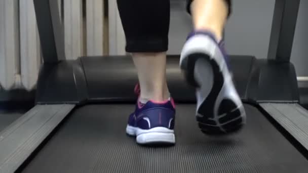 Кадри жінки, що йдуть на біговій доріжці в спортзалі — стокове відео