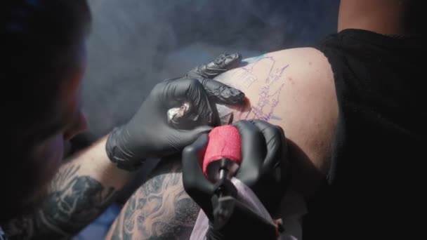 Filmato di un tatuatore che si fa un tatuaggio su una spalla di un uomo in un salone — Video Stock