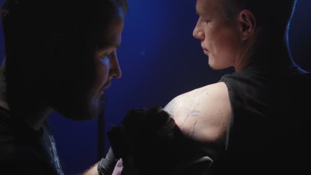 Video di un maestro che si fa un tatuaggio su una spalla di un uomo in un salone — Video Stock