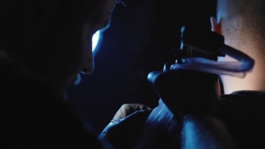 Genç bir adamın omzunda dövme yapan bir dövmenin görüntüsü.