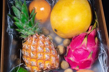 Farklı egzotik meyvelerin dumanlandığı ahşap bir kutu resmi