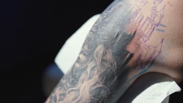 Videó egy tetoválásról, amin egy fiatal férfi vállára tetoválnak egy szalonban.