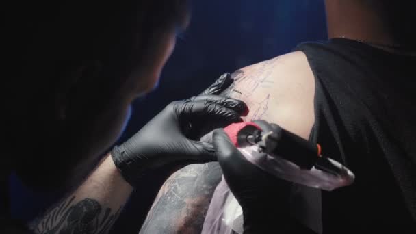 Мастер делает татуировку на плече человека — стоковое видео