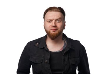 Siyah kot ceketli, sakallı, kaşlarını çatmış adamın fotoğrafı.