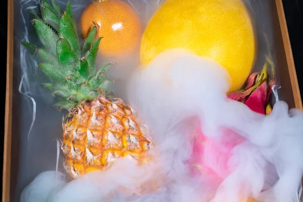 Caja de madera con diferentes frutas exóticas en humo —  Fotos de Stock