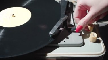 Kırmızı tırnaklı bir kızın retro gramofonu açması.