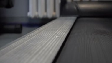 Spor salonunda koşu bandında yürüyen videolu kadın.