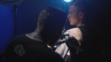 Bir adamın omzuna dövme yaptıran bir ustanın videosu.