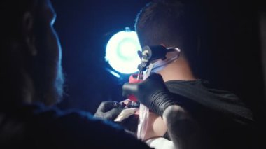 Erkek omzuna dövme yaptıran bir dövmenin görüntüsü.