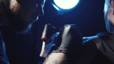 Bir erkeğin omzunda dövme yapan bir dövmenin görüntüsü.