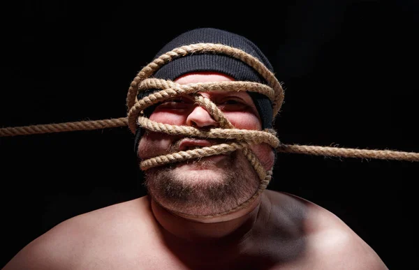 Porträtt av bunden fet man i mössa med rep i ansiktet — Stockfoto
