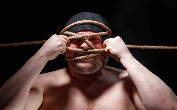 Picture of binded fat man in cap with rope on face — Stock Photo, Image