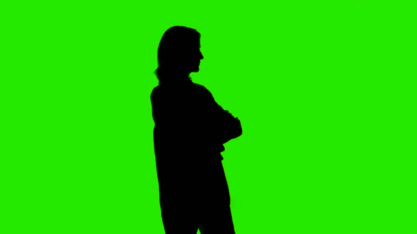 Ženy čekající siluetu v bundě s rukama zkříženýma na zeleném pozadí — Stock video