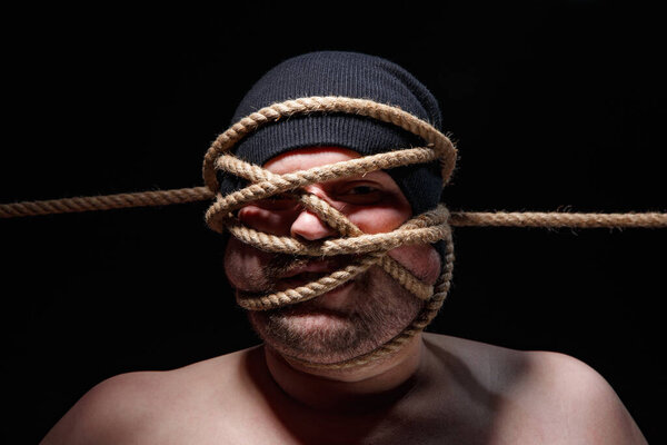 Photo of binded fat man in cap with rope on face