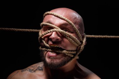 Yüzünde ip olan bağlanmış kel bir adamın fotoğrafı.
