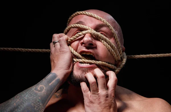 Photo of binded bald man trying tear the rope on face — Stock Photo, Image