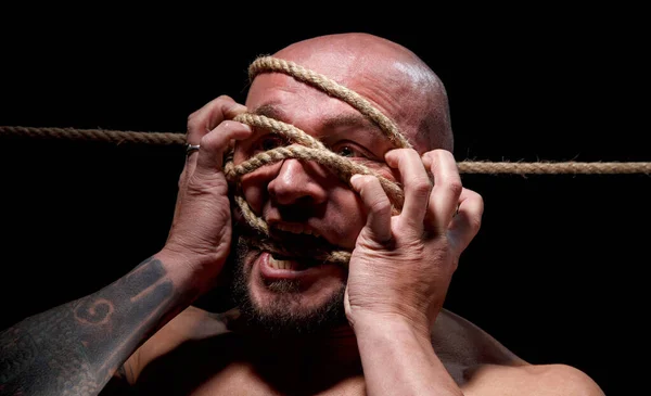 Изображение обвязанного кричащего лысого человека с веревкой на лице — стоковое фото