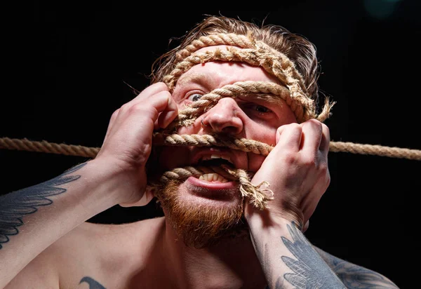 Immagine di un uomo tatuato legato che cerca di strappare la corda sul viso — Foto Stock