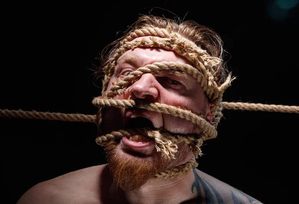 Portrait of binded tattooed screaming man with rope on face — Stock Photo, Image