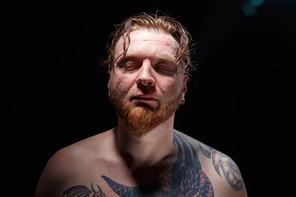 Foto di uomo tatuato con gli occhi chiusi su sfondo nero — Foto Stock