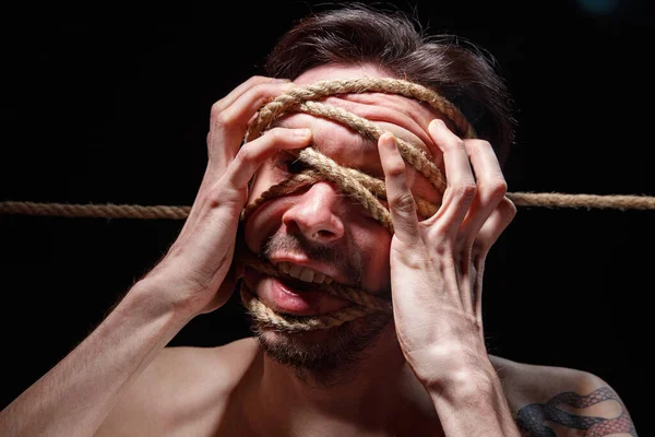 Image of binded brunette man trying tear the rope on face — Stock Photo, Image