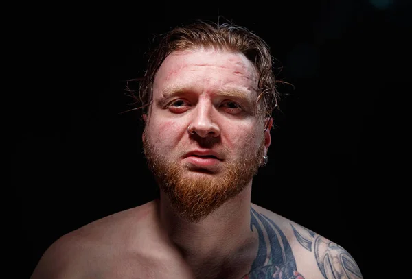 Портрет татуированного мужчины с рыжими волосами на черном фоне — стоковое фото