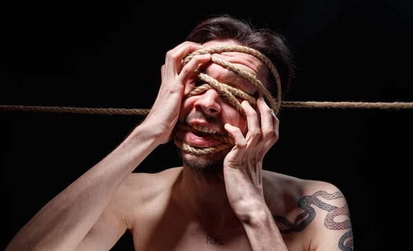 Photo of binded brunette man trying tear the rope on face — Stock Photo, Image