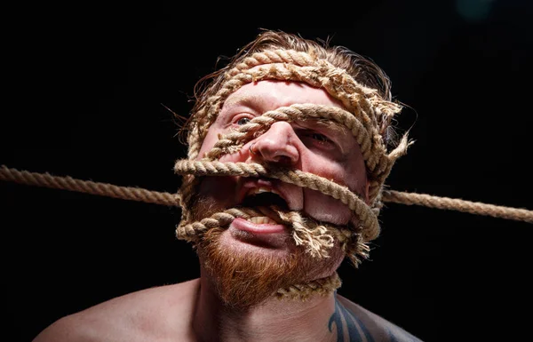 Foto di uomo urlante tatuato legato con corda sul viso — Foto Stock