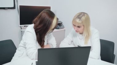 İki kadın ofiste iş konuşuyor.