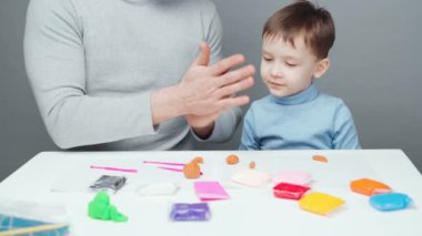 Baba ve oğlunun gri arka planda plastik oyuncaklar yonttuğu görüntüler.