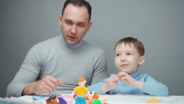 Videó apáról és kisfiúról, amint állatokat csinálnak plasztikából. — Stock videók