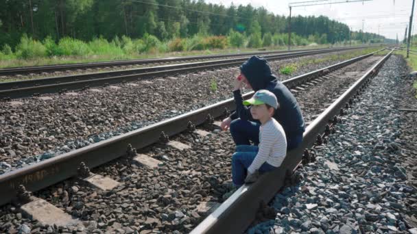 年轻妇女和男孩坐在铁轨上的录像 — 图库视频影像