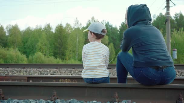 妇女和男孩坐在铁轨上的录像 — 图库视频影像