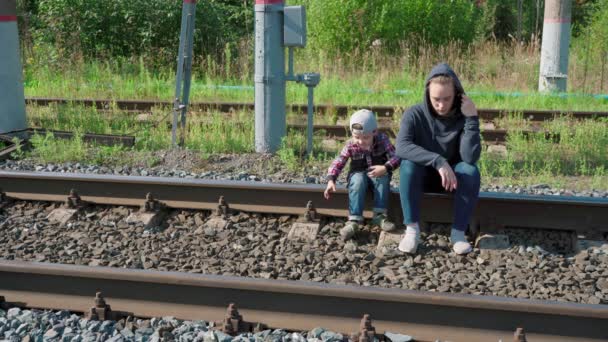 Młoda kobieta i chłopiec siedzą na torach — Wideo stockowe