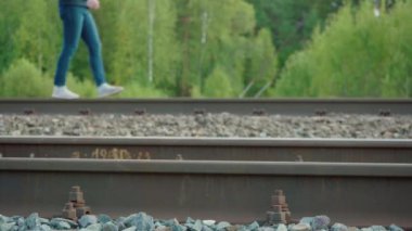 Yazın demiryolunda yürüyen bir kızın videosu.