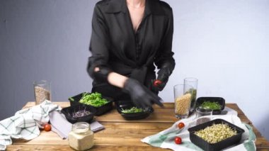 Siyah elbiseli bir kadının mikro yeşil ve tohumlu salata pişirdiği video.