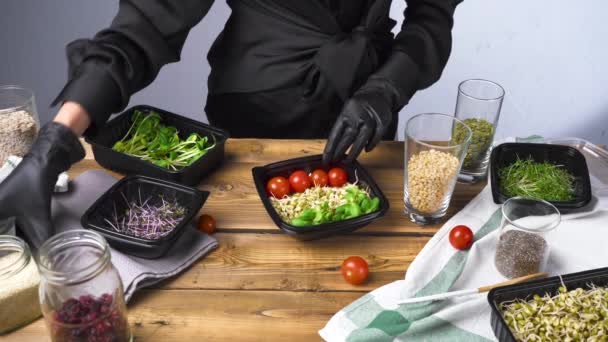Felvételek egy fekete ruhás nőről, amint salátát főz mikrozölddel és magokkal