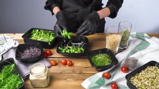 Schieten van de vrouw in zwarte handschoenen koken salade met micro groen — Stockvideo