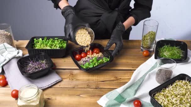 Tiro de mulher em luvas pretas salada de cozinha com micro verde e sementes — Vídeo de Stock