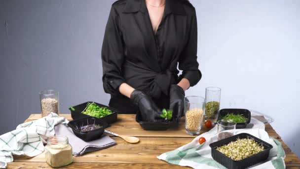 Tiro de mujer en ensalada de cocina vestido negro con micro verde y semillas — Vídeos de Stock