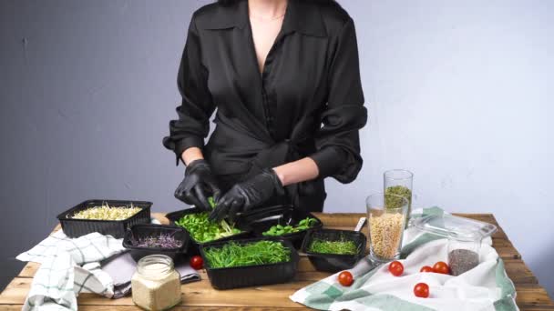 Tiro de mujer en ensalada de cocina vestido negro con micro verde — Vídeo de stock