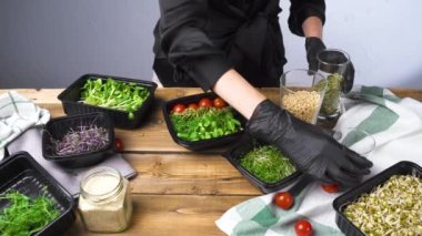 Siyah eldivenli bir kadın mikro yeşil salata pişiriyor.