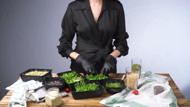 Видеозапись женщины в черном платье, готовящей салат с микро-зеленым — стоковое видео