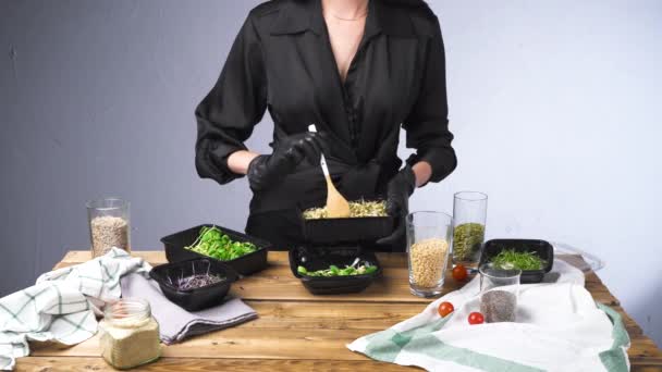 Filmación de la mujer en ensalada de cocina vestido negro con micro verde y semillas — Vídeos de Stock