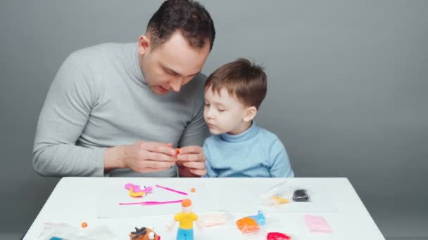 Видео отца и сына, делающих игрушки из пластилина — стоковое видео