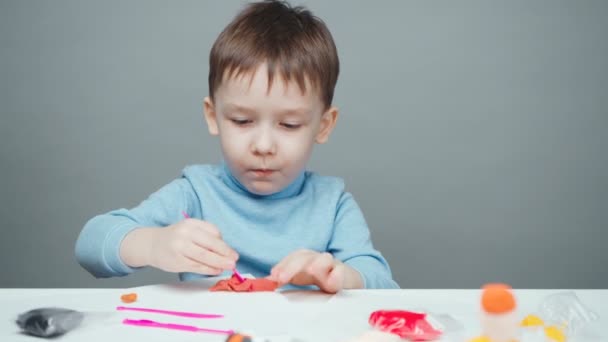 Gri arka planda plastik heykel yapan küçük çocuk. — Stok video