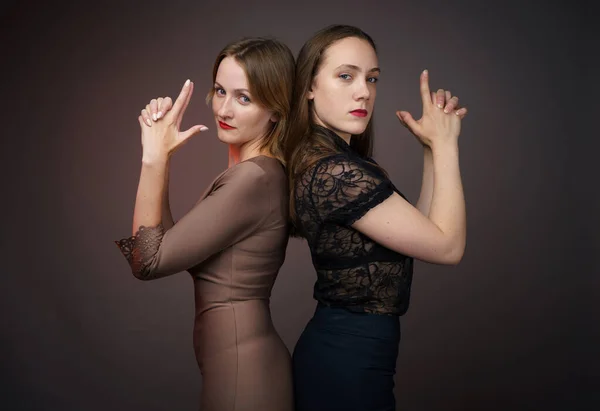 Dvě kamarádky ženy stojí zády k sobě na šedém pozadí — Stock fotografie