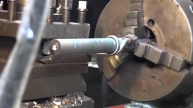 Torna tezgahında metal spiral yapan bir adamın görüntüsü.